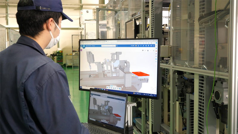 Worker on shopfloor looking at screen showing a SOLIDWORKS 3D model of industrial machine