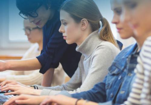 A teacher next to a student typing 