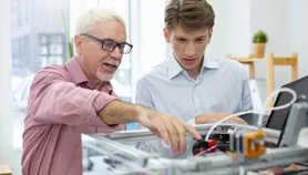 Teacher pointing out machine design to student - SOLIDWORKS